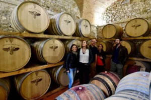 Tour guests gathered in front of wine barrels in the wine cellar at Castello di Bolgheri Estate