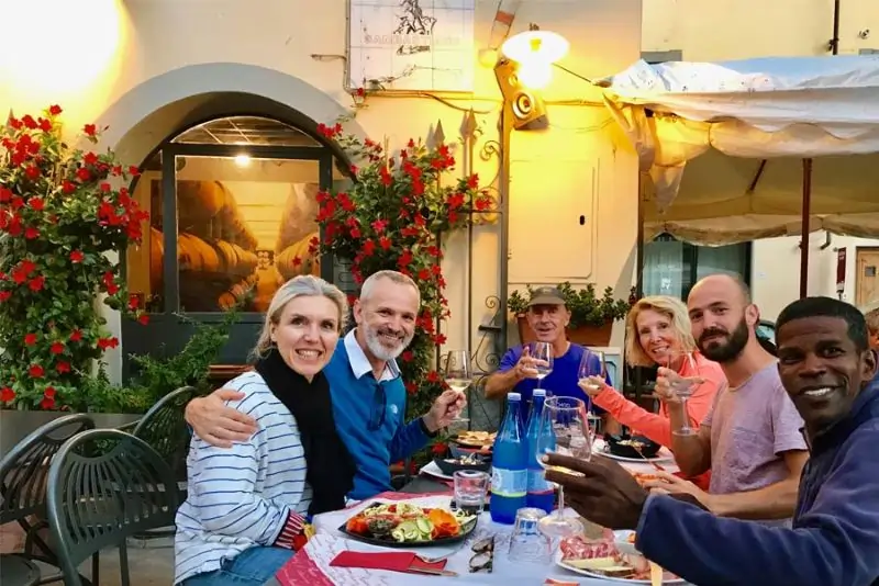 Tuscan food and wine tour guests enjoying tuscan wine and food in old town of Bolgheri